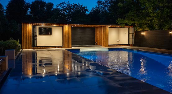 Illuminated Bear garden room beside a swimming pool at dusk