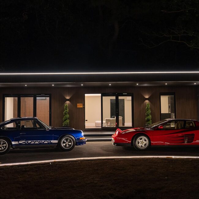 The Hanger luxury suite build illuminated at night with two classic cars